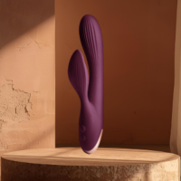 Burgandy and rose gold vibrator on a wooden platform with a brown background